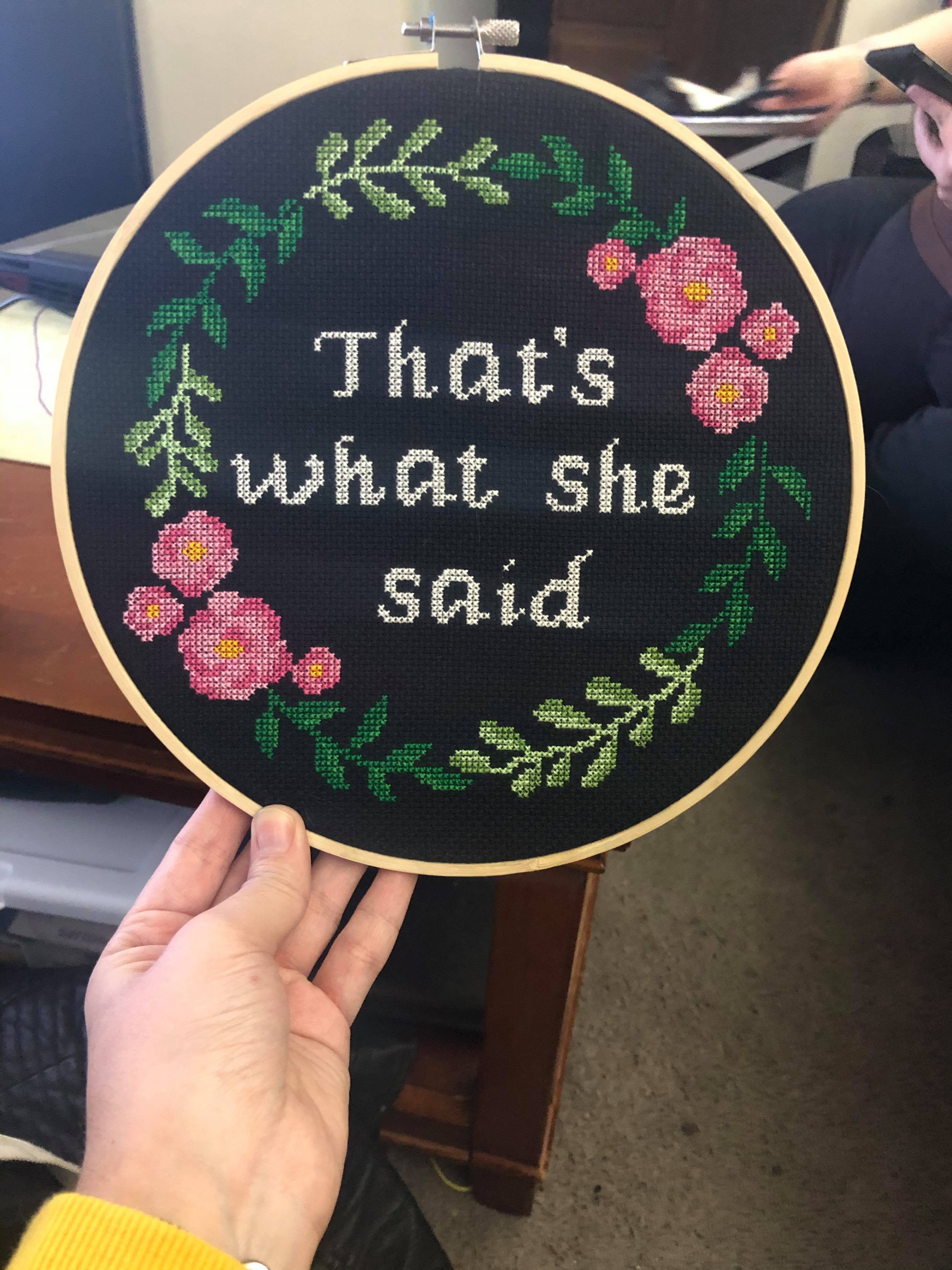 A cross stitch with a ring of vines and flowers and the words That's what she said in the middle